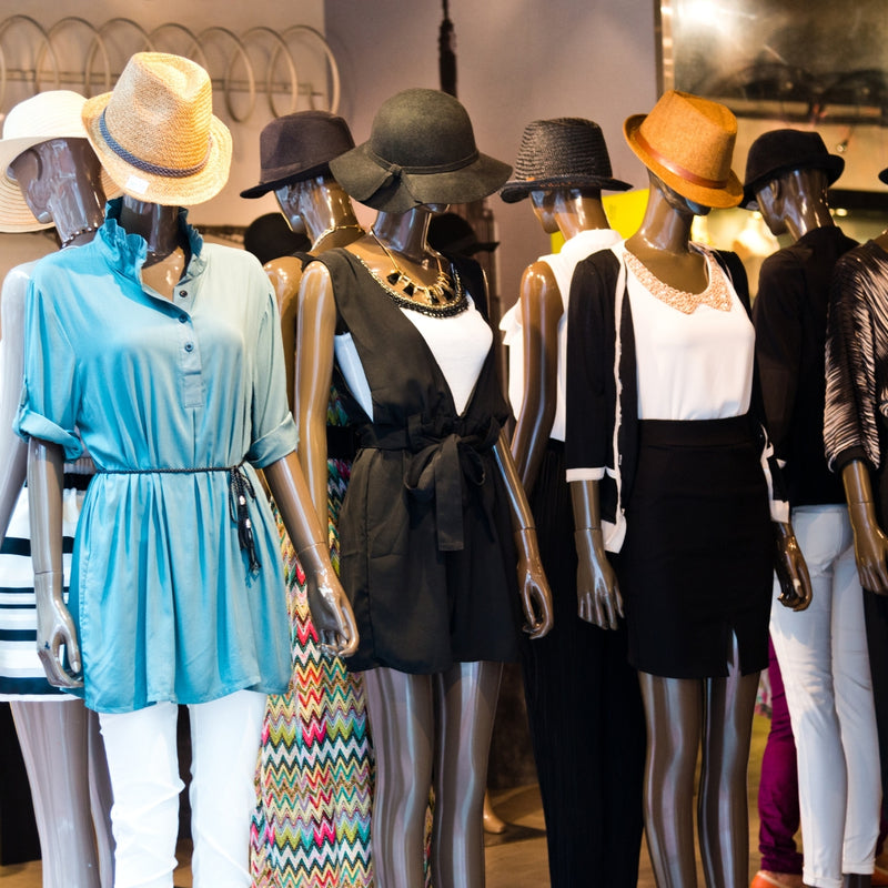 Mannequins wearing various outfits with hats in a store setting